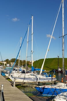 Klaipeda, Lithuania - August 11, 2023: A group of sailboats are secured to a pier, their masts reaching towards the sky as they rest on calm waters.