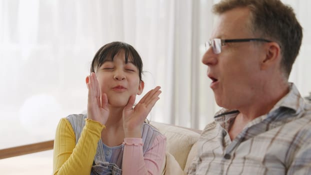 Grandfather and granddaughter together watch interesting entertainment media on TV. Old senior use technology communicate with young generation cross generation gap strengthen family bond. Divergence.