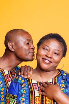 Black man sharing romantic secret with smiling wife, whispering message in ear. Happy african american boyfriend and girlfriend couple having quiet private communication portrait