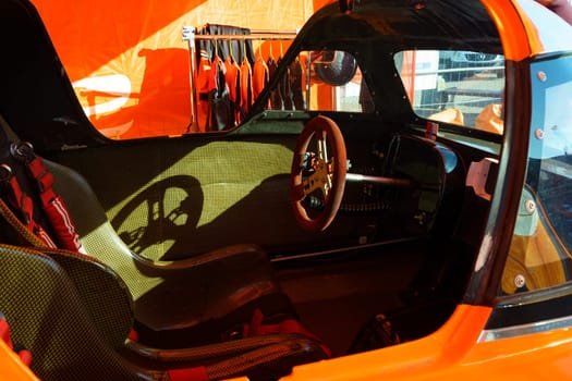 The interior of an orange car is shown, featuring a steering wheel and dashboard.