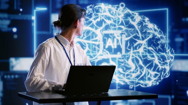 Admin using laptop to visualize artificial intelligence neural networks made up of interconnected nodes using AR holographic technology. Inspector overseeing AI systems processing information