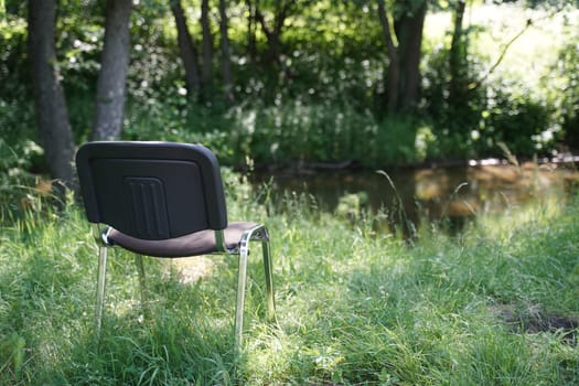 A black chair placed atop a vibrant green field.
