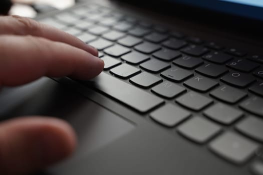 A close-up view of a person focusing on typing on a laptop keyboard.