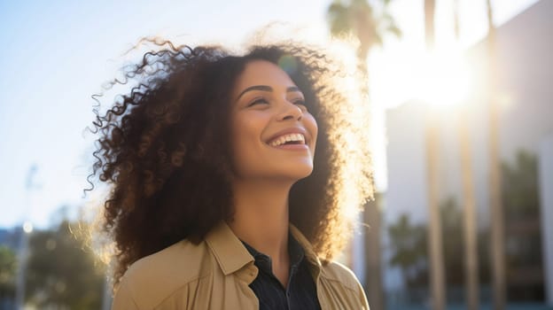 Inspired happy laughing hispanic young woman with curly hair enjoys a summer walk in sunny city