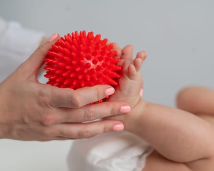 A doctor massages a baby's foot using a spiked ball