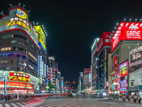 tokyo, japan - apr 28 2024: Tourists at Kabukicho pedestrian crossing juncting the Shinjuku Moa 2 Avenue and the Godzilla Road famous for its Don Quijote store in the red-light district at night.