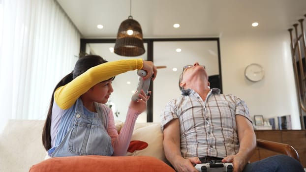 Grandfather and granddaughter together play console game, entertainment media. Old senior use technology communicate with new generation kid cross generation gap strengthen family bond. Divergence.