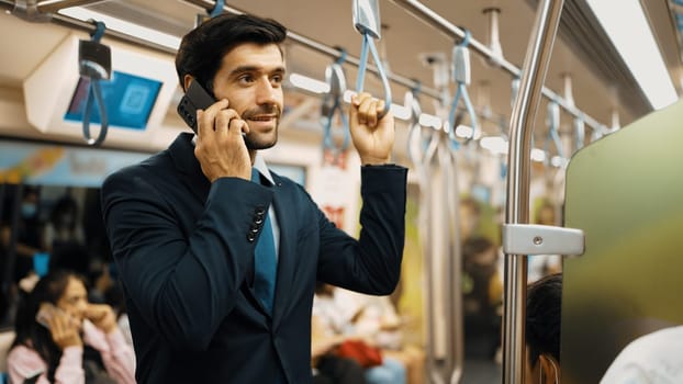 Smart business man phone calling to project manager while standing in train. Professional male leader talking to investor about marketing plan by using phone with blurring background. Exultant.