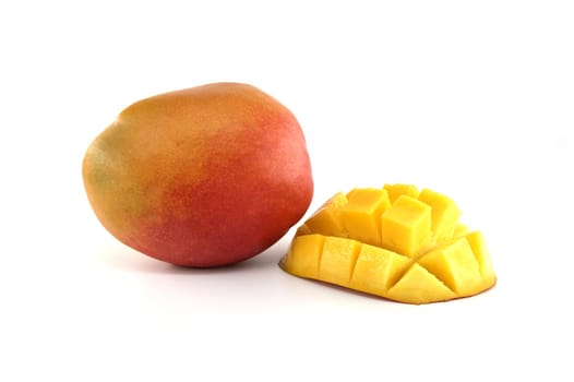 Ripe mango with red and yellow skin near cut half mango with the flesh cubed
