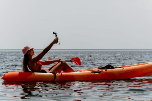 Happy smiling woman in kayak on ocean, paddling with wooden oar. Calm sea water and horizon in background