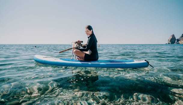 Sea woman sup. A happy positive woman in hat with family relaxing in sea, aerial back view of family on SUP board floating on calm water. Active lifestyle at sea. Summer vacation. Slow motion