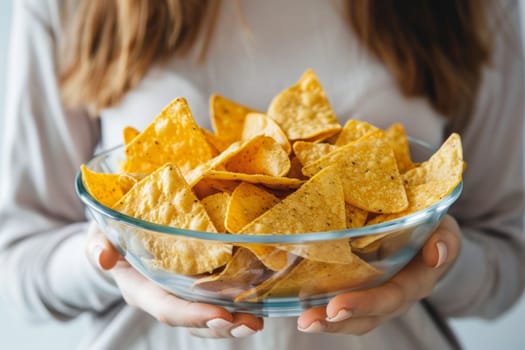 Close up of woman holding a transparent bowl of nachos.