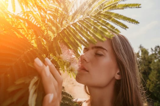 Beauty portrait of young woman closeup. Young girl smelling Chinese acacia pink blossoming flowers. Portrait of young woman in blooming spring, summer garden. Romantic vibe. Female and nature.