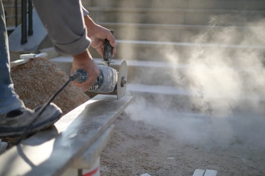 A man is using a grinder to cut a piece of concrete,