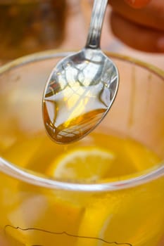 pouring honey in a cup of tea .