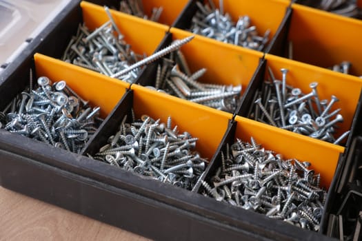 A wood flooring with a toolbox containing screws and drills.