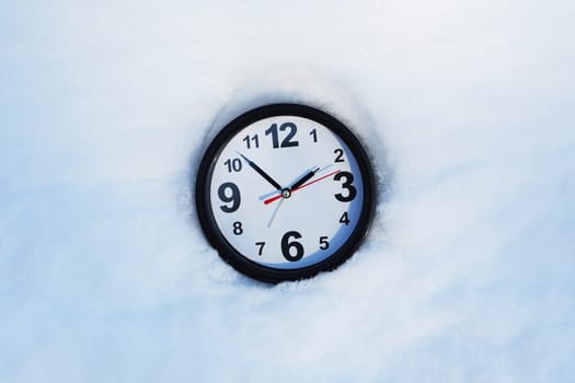 Time concept. Clocks in the snow with free space