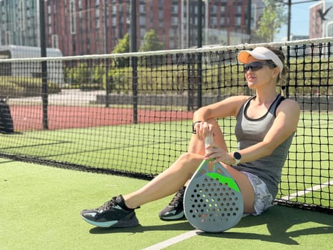Happy female paddle tennis player during practice on outdoor court. Copy space. High quality photo