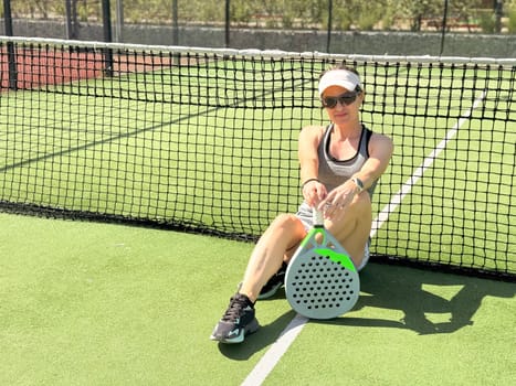 Portrait of active emotional woman playing padel tennis on open court in summer, swinging racket to return ball over net .. High quality photo