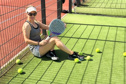 Woman playing padel in a grass padel court indoor - Young sporty woman padel player hitting ball with a racket. High quality photo