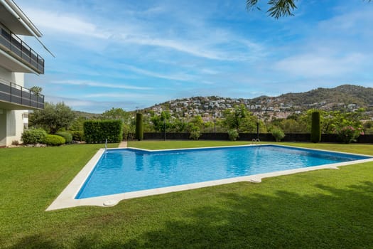 A pristine pool offering a refreshing escape, framed by green lawns and mountain vistas.