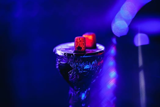 bowl of the hookah with hot coals on the foil for Smoking and relaxing with a blue background