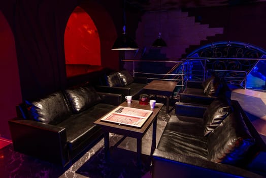 relaxation room with a modern design in a cafe with a dark lighting with sofas and tables without people