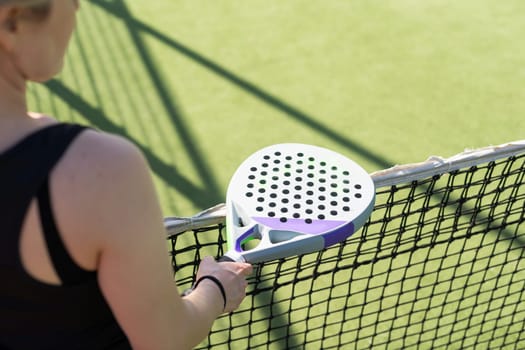 hands of a woman paddle player is holding balls and the racket at the background at the beginning of the match outdoors . High quality photo