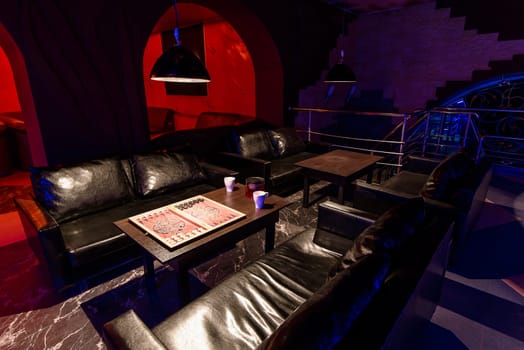 relaxation room with contemporary dark design illuminated in a cafe with a table with tea and backgammon to relax