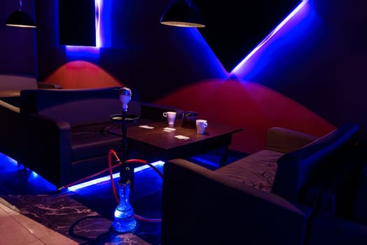 relaxation room with a hookah and tea with tables and a sofa for relaxing in a cafe with glow