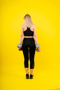 Strong woman working out with dumbbells, flexing her arm. Photo of sporty female in a sportswear.