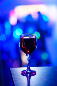 glass of red wine at a party on blurred blue background