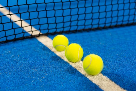 balls near the net of a blue padel tennis court. High quality photo