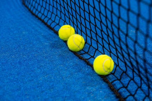 balls near the net of a blue padel tennis court. High quality photo