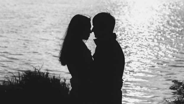 couple in love hugging by the water, the silhouette
