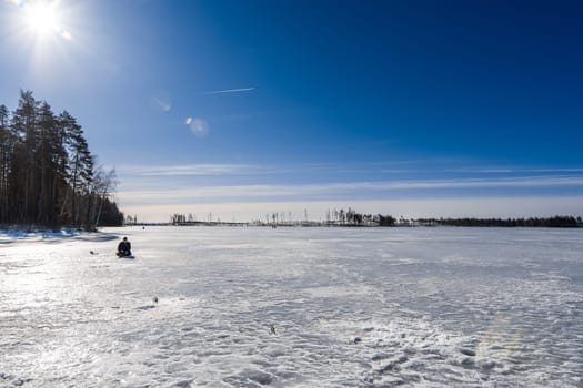 lonely fisherman is fishing in the winter on a Sunny day