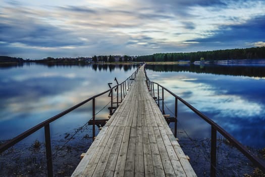 old wooden bridge over the river in the evening in summer