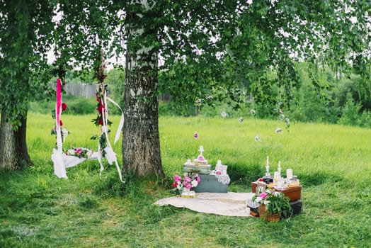 decorated area for the wedding with swings, flowers, and decorations outdoors under a tree