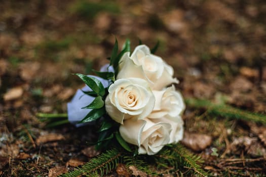 wedding bouquet of white roses lies on the leaves in autumn