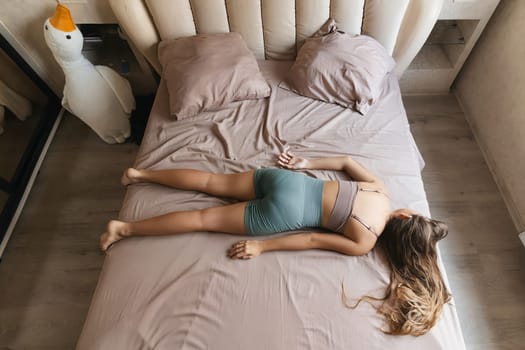 A girl is laying on a bed with her head on a pillow. The bed is covered in a pink blanket