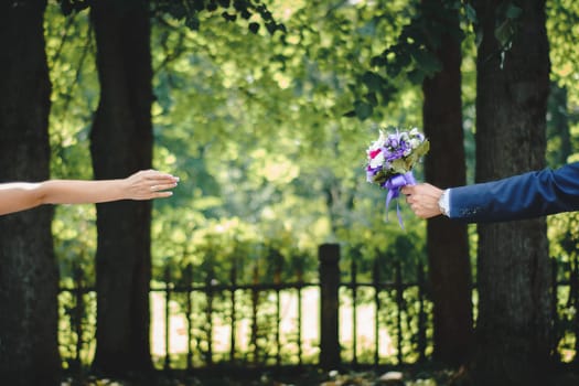 groom's hand hands the bride a wedding bouquet at the wedding ceremony