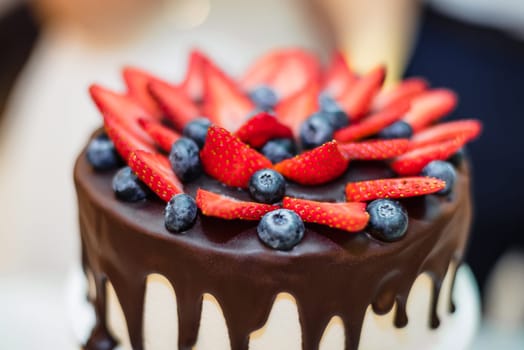 strawberry and bilberry berries on a chocolate icing cake closeup