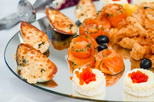 pieces of red cooked salmon and mussels are beautiful on a plate for a holiday dinner