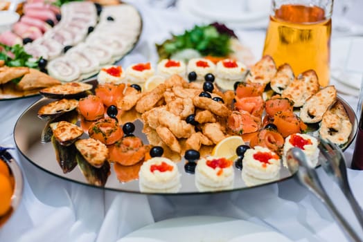 fish dishes of salmon, mussels and caviar with olives on a plate in the restaurant