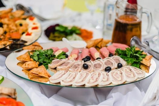 appetizing fresh pieces of meat on a plate in the restaurant with herbs and olives