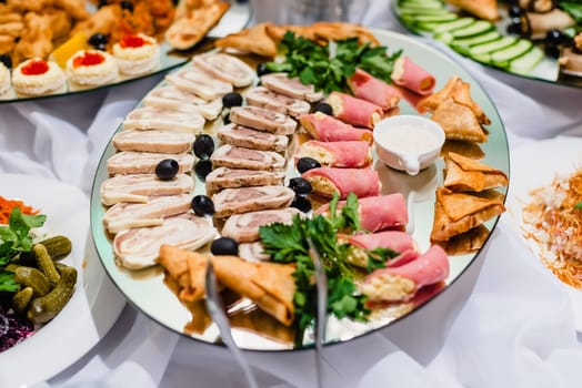 cold cuts of meats on the plate with sauce and olives in the restaurant