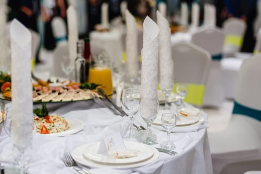 white festive laid table in the restaurant with glasses and plates prepared for dinner