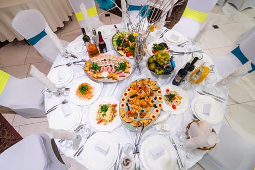 festive white table with food and drinks in the restaurant for a wedding event