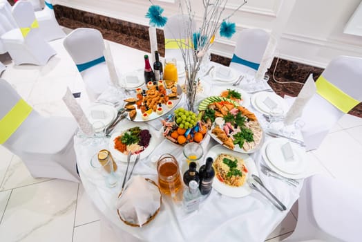 festive chic white table with food and drinks for the gala dinner in the restaurant