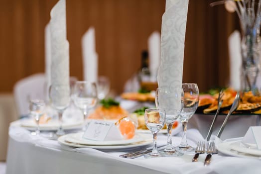 empty wine glasses and other utensils on the white festive table in the restaurant